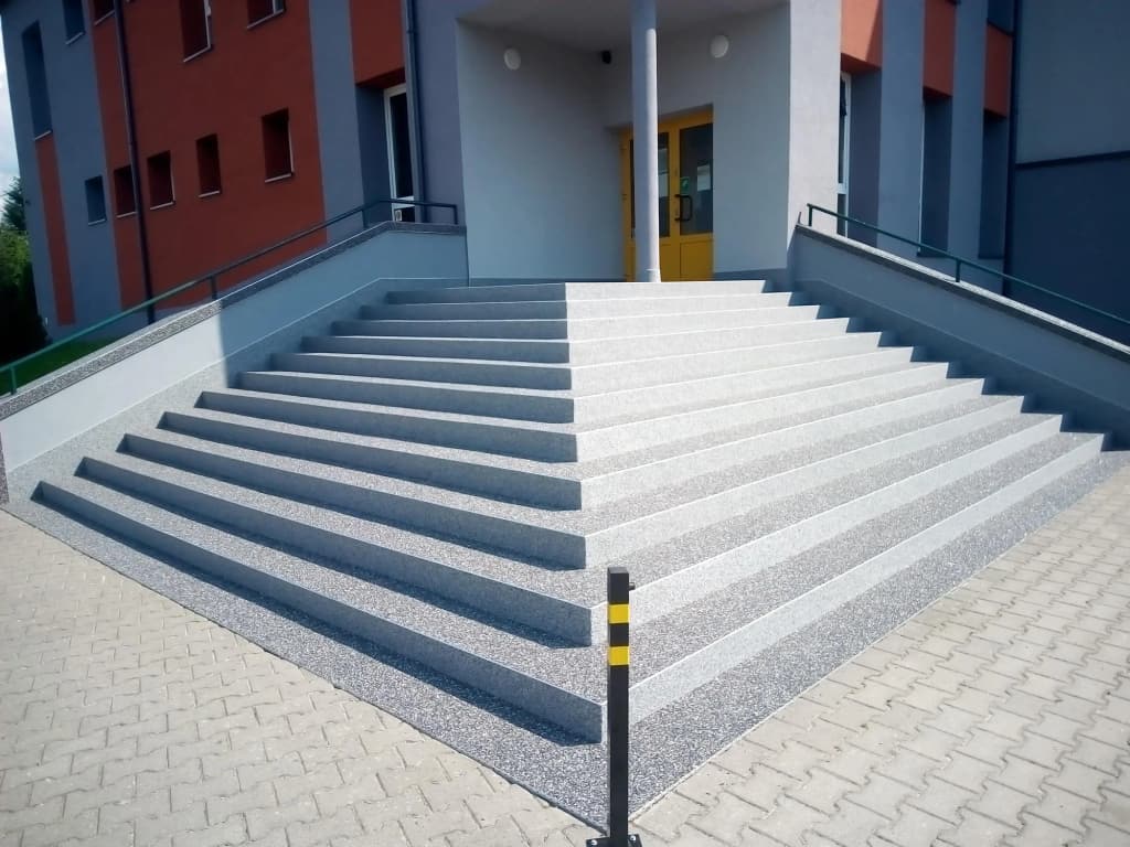 Szerokie schody wejściowe z kamiennego dywanu w kolorze szarym i białym
