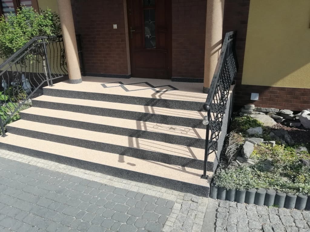 Beżowo-grafitowy kamienny dywan na schodach wejściowych z wzorem