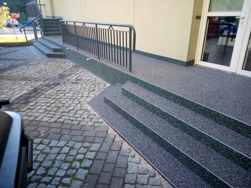 Kamienny dywan na schodach i pochylni przy wejściu do budynku