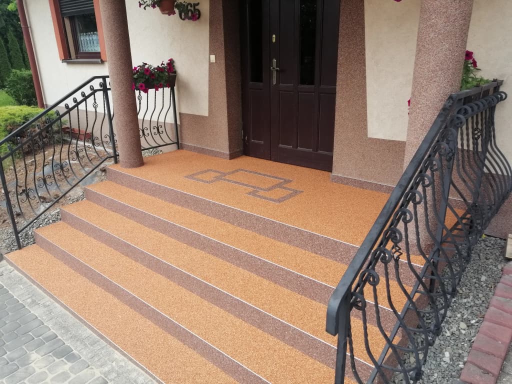 Pomarańczowy kamienny dywan na podeście wejściowym z geometrycznym wzorem