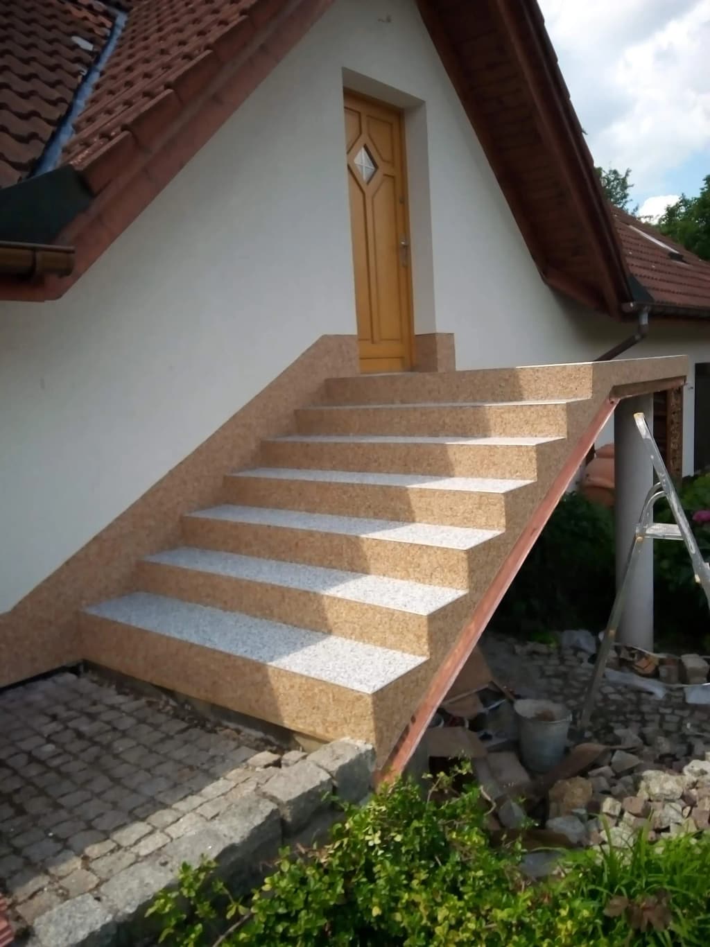 Schody wejściowe wykończone kamiennym dywanem w kolorze beżowym i szarym