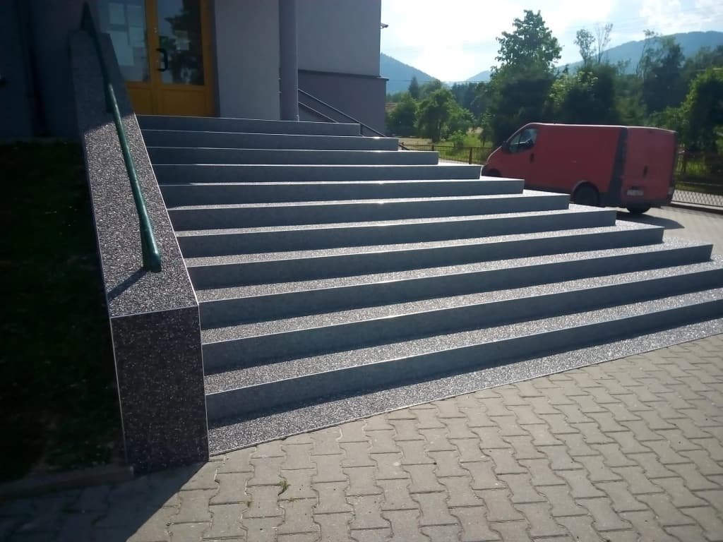 Kamienny dywan na schodach wejściowych do budynku, widok od strony podjazdu