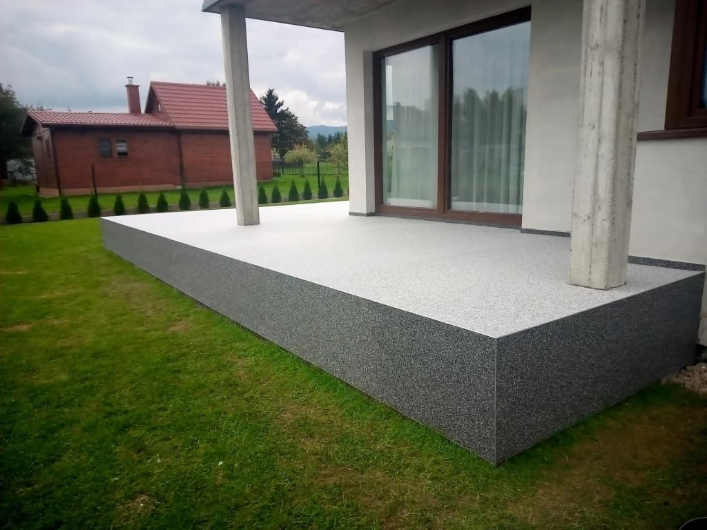 Kamienny dywan na zadaszonym tarasie z betonowymi słupami