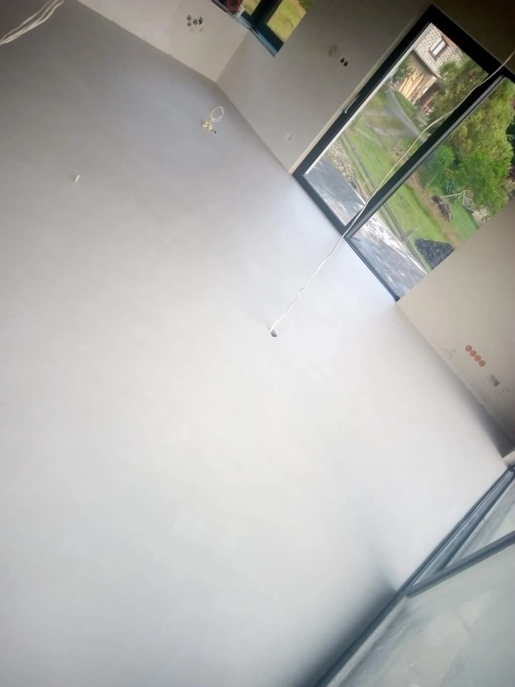 Podłoga z mikrocementu przy przeszkleniu, z widocznymi chmurkami materiału