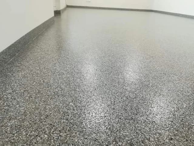 Zbliżenie na strukturę posadzki żywicznej z posypką kwarcową w odcieniach szarości