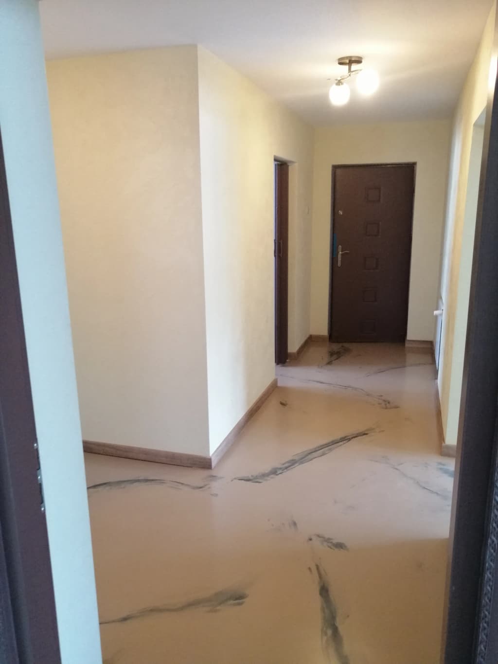 Beżowa posadzka żywiczna z żyłkowaniem w przedpokoju mieszkania