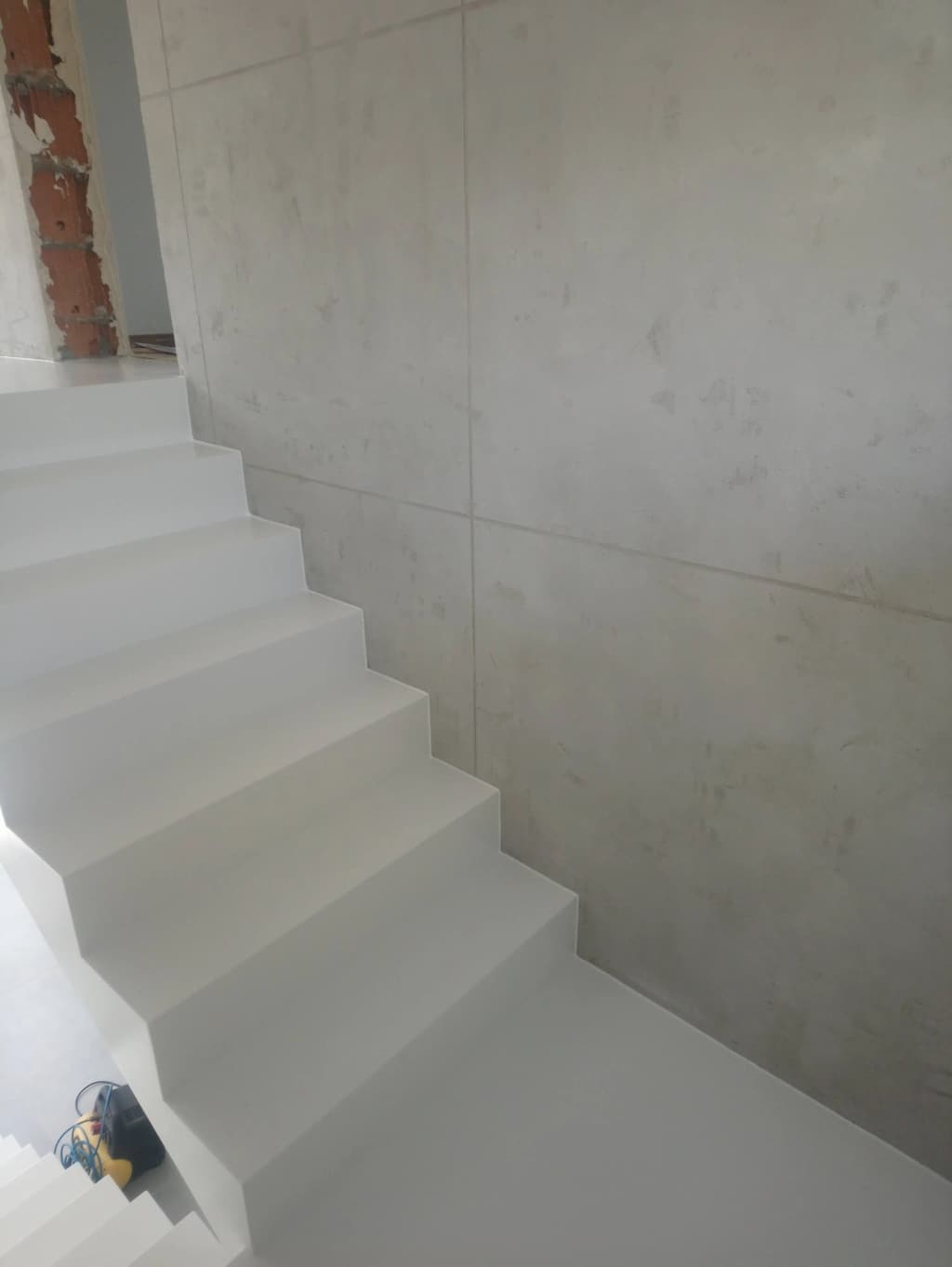 Jasne schody żywiczne wzdłuż ściany z płyt betonu architektonicznego